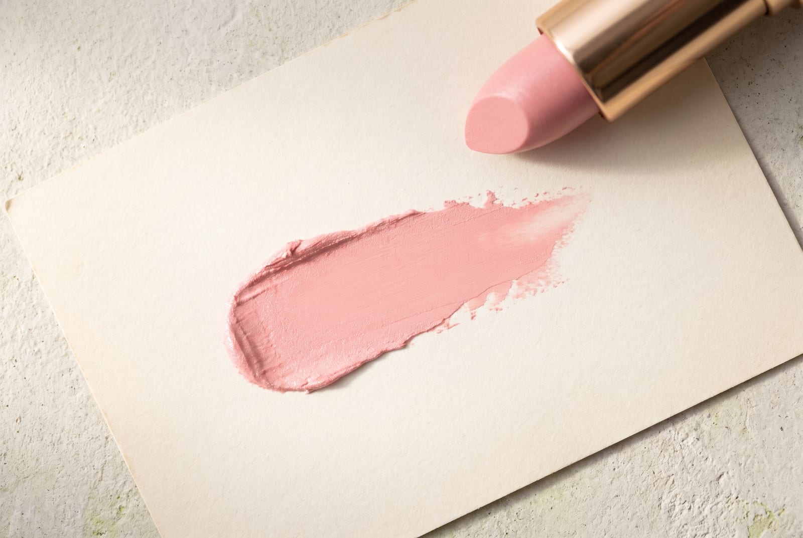 A light spring beauty macro: a single palette-hex pigment detail at extreme close-up, a peach or warm-coral cream caught in soft, bright daylight against a pale plaster background.