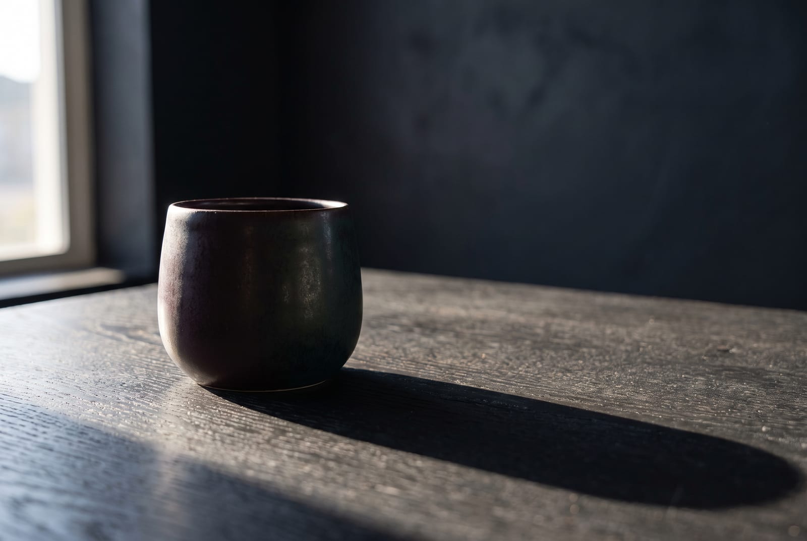 A deep winter single-object study: one palette-hex subject (a folded emerald knit or a small faceted sapphire-glass object) on black slate with generous negative space, intentionally quiet after the 24-swatch color block.
