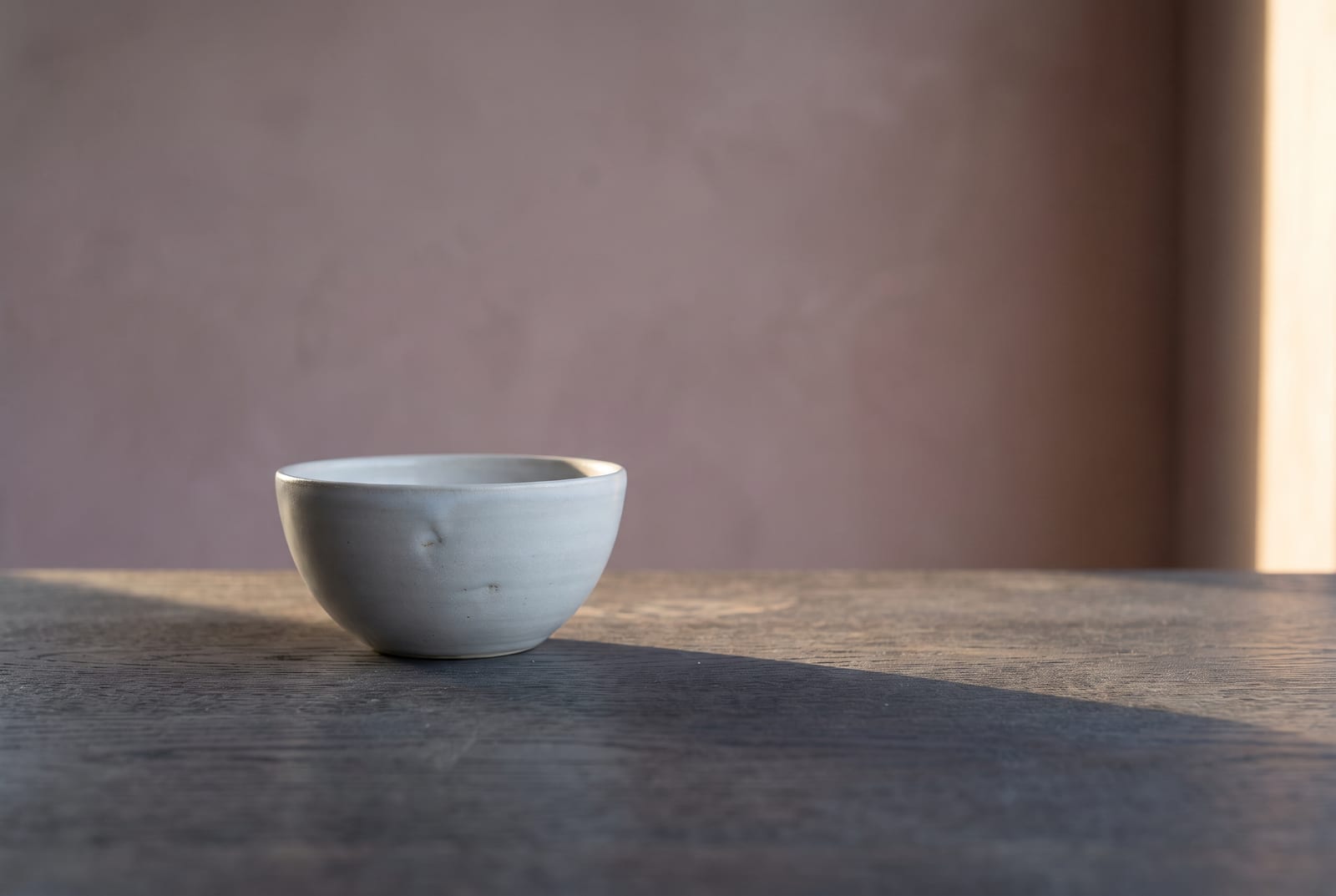 A cool summer single-object study: one palette-hex subject (a folded slate-blue knit or a small cool-gray ceramic) on cool pale plaster with generous negative space, intentionally quiet after the 24-swatch color block.
