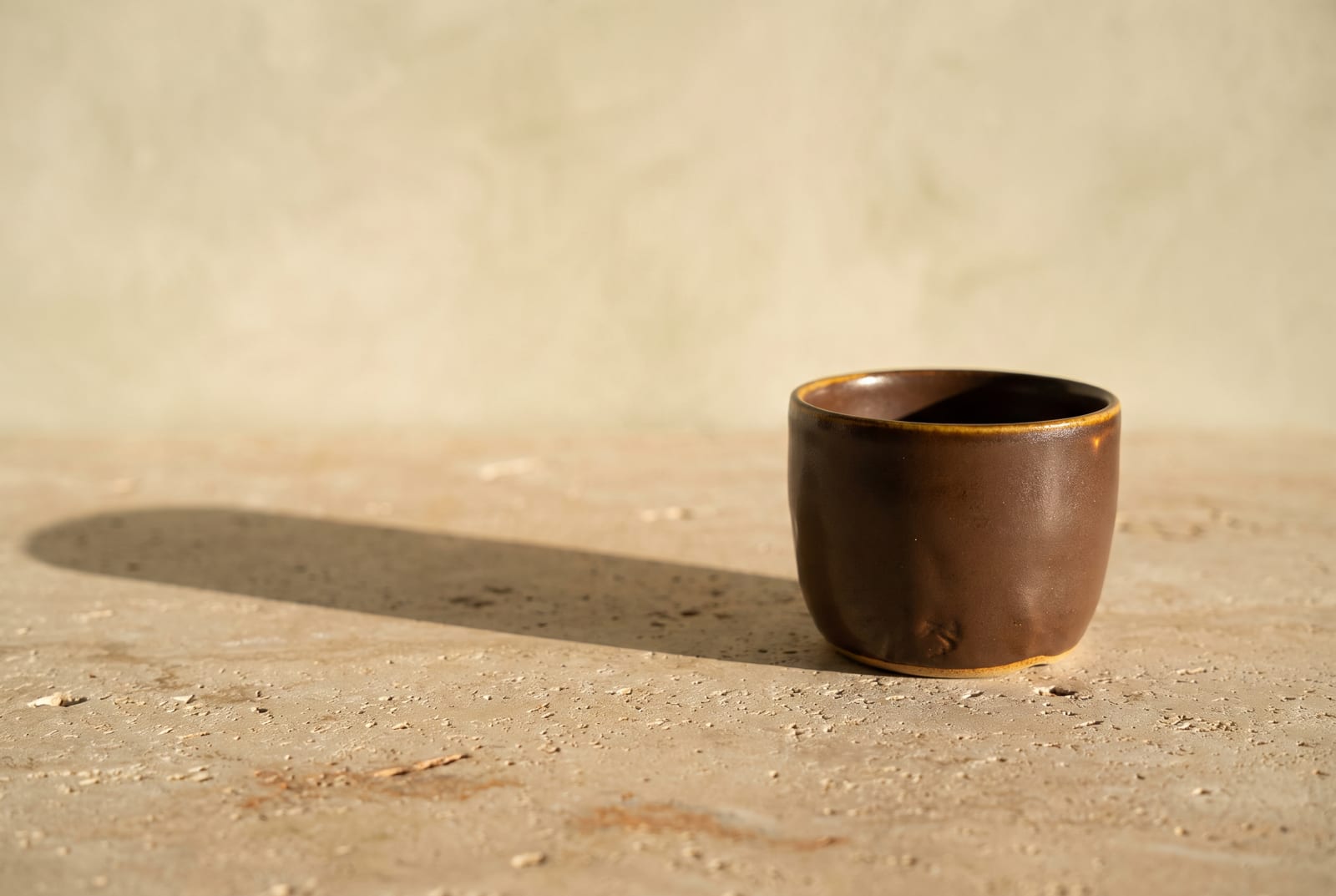 A warm autumn single-object study: one palette-hex subject (a folded rust knit or a small bronze vessel) on raw plaster with generous negative space, intentionally quiet after the 24-swatch color block.