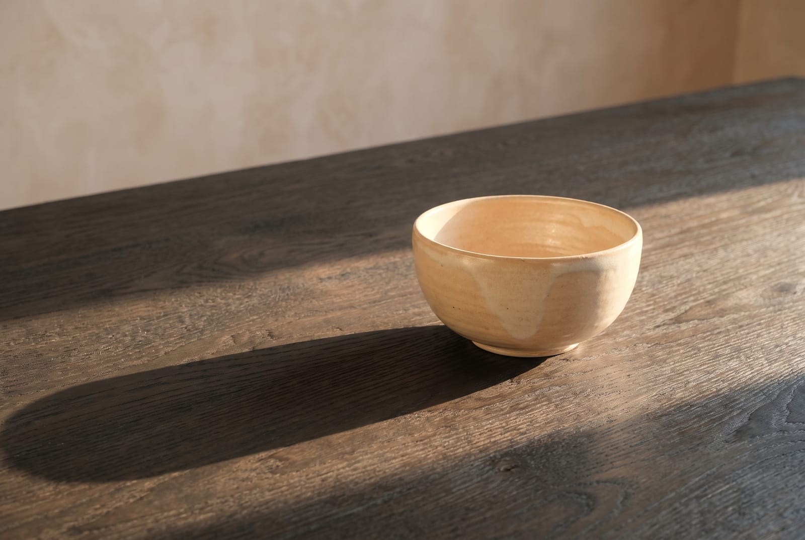 A warm spring single-object study: one palette-hex subject (a folded golden-yellow knit or a small coral vessel) on warm cream plaster with generous negative space, intentionally quiet after the 24-swatch color block.