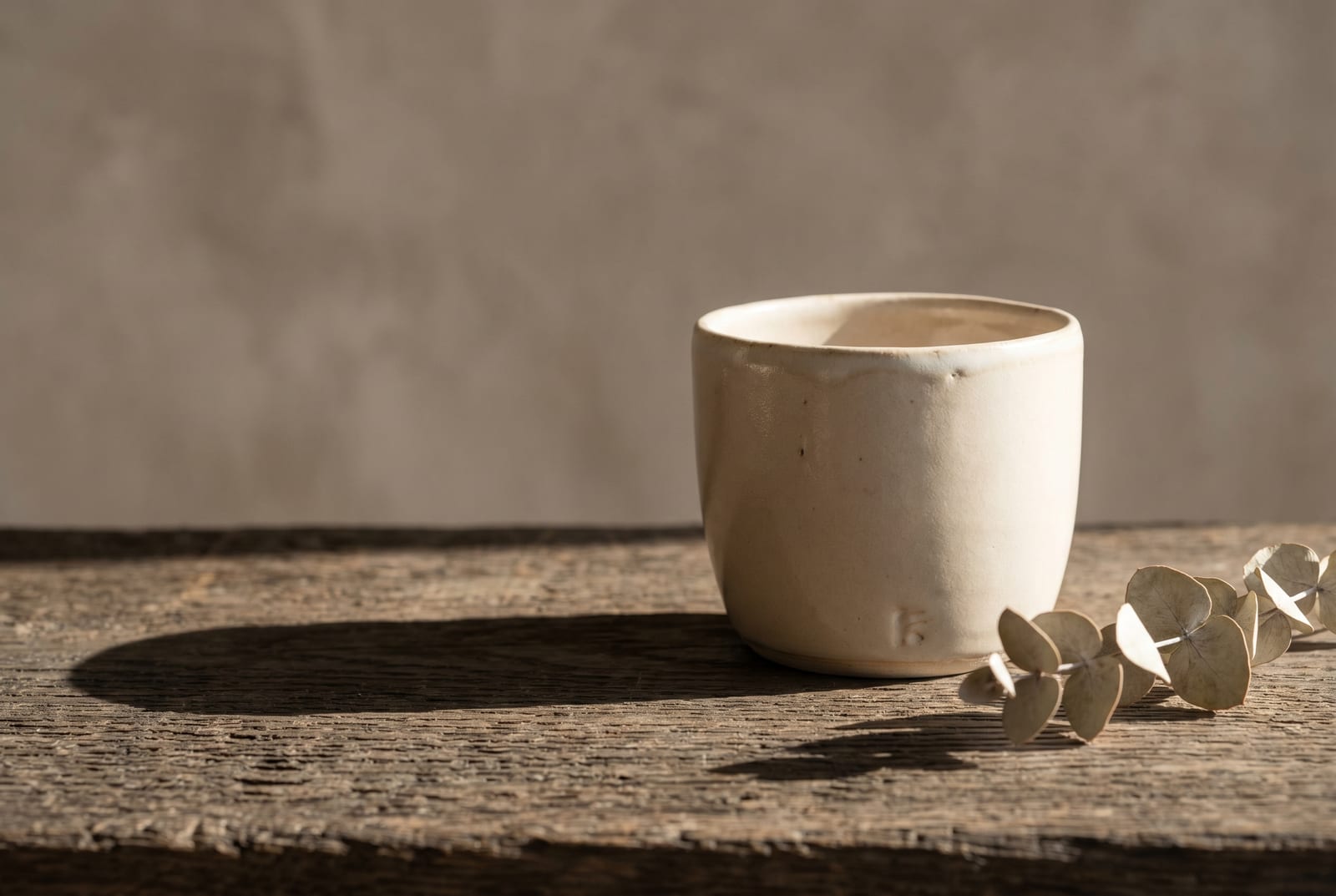 A soft autumn single-object study: one palette-hex subject (a folded camel knit or a small bronze vessel) on raw plaster with generous negative space, intentionally quiet after the 24-swatch color block.